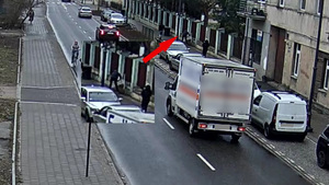 Zdjęcie z monitoringu, wzdłuż jezdni stoją zaparkowane samochody, chodnikiem idą sprawcy  niosący skradziona drabinę.