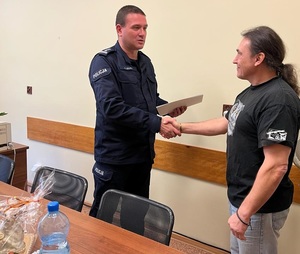 Inspektor Dariusz Dziurka przekazuje gratulacje mężczyźnie.
