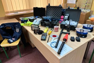 Na stole leżą elementy wyposażenia i ubioru policjanta.
