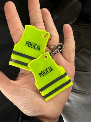 Na dłoni leżą dwa odblaski w kształcie kamizelki z napisem policja.