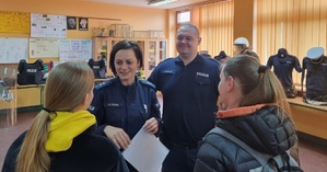 Policjanci rozmawiają z dwiema osobami odwiedzającymi szkołę.