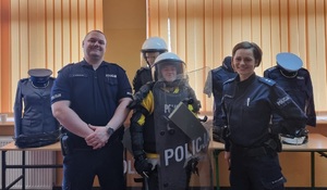 Policjanci pozują do zdjęcia z uczestnikiem spotkania ubranym w elementy umundurowania.