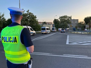 Policjant ruchu drogowego na tle radiowozów.