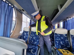 Policjant z łódzkiej drogówki kontroluje wnętrze autokaru.