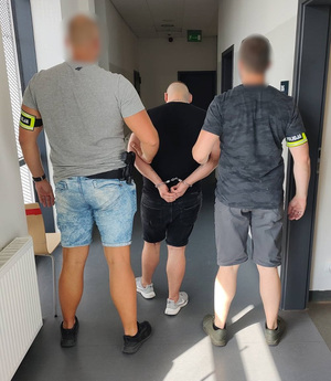 Policjanci prowadzą korytarzem komisariatu zatrzymanego.