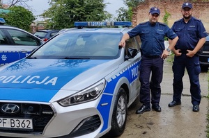 Policjanci z bałuckiego komisariatu, którzy eskortowali dziecko stoją przy radiowozie.