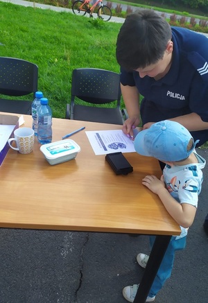 Policjantka pobiera odbitkę linii papilarnych małego chłopca.
