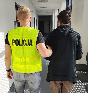 Policjant trzyma zatrzymanego mężczyznę.