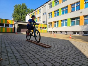 Chłopiec w kasku ochronnym jedzie na rowerze po torze z przeszkodami.