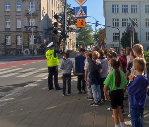 Policjantka omawia z dziećmi zasady działania sygnalizacji świetlnej.