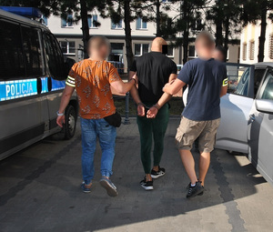 Policjanci prowadza zatrzymanego.