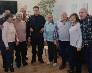 Uczestnicy spotkania i policjant na zdjęciu pamiątkowym.