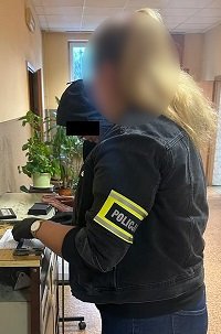 Policjantka pobiera odciski palców od zatrzymanego.