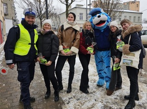 Policjant wspólnie z Kotem Prewencjuszem stoją w towarzystwie nagrodzonych pieszych.