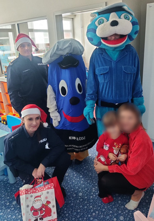 Policjanci wraz z maskotkami pozują do zdjęcia z dzieckiem i jego opiekunką.