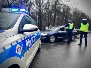 Policjanci z łódzkiej drogówki stoją przy kierującym samochodem osobowym.