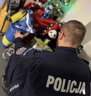 Policjant kuca przy darach dla schroniska.