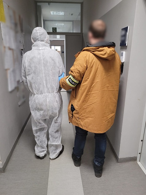 Policjant prowadzi zatrzymanego.