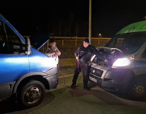 Policjant odpina kable rozruchowe po uruchomieniu drugiego pojazdu.
