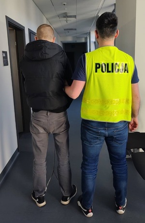 Zatrzymany prowadzony przez policjanta.