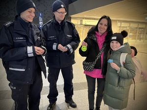 Policjanci wręczają odblaski osobom przebywającym na dworcu fabrycznym.