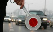 Policjant trzyma tarczę do zatrzymywania pojazdów.