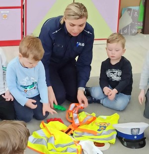 Policjantka pokazuje odblaski przedszkolakom.