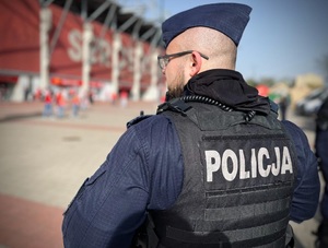 Policjant obserwuje kibiców drużyny gospodarzy.