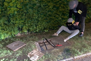 Policjant trzyma zatrzymanego mężczyznę.