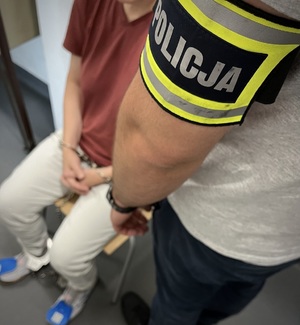 Policjant pilnuje zatrzymanej kobiety.