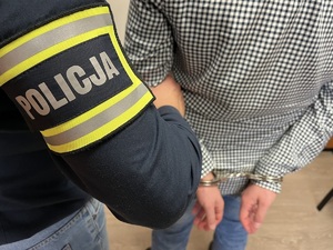 Zdjęcie poglądowe zatrzymanego trzymanego przez policjanta.
