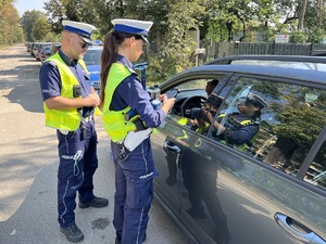 Umundurowani policjanci ruchu drogowego w trakcie kontroli pojazdu.