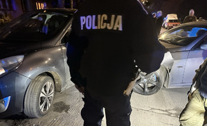 Policjant stoi przed uszkodzonymi pojazdami.