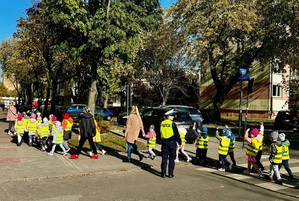 Policjantka uczy przedszkolaki jak prawidłowo przechodzić przez przejście dla pieszych.