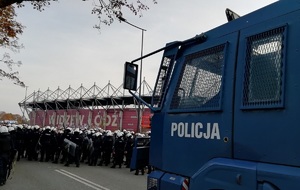 Armatka wodna z napisem &quot;policja&quot; na tle stadionu i policjantów z Oddziału Prewencji Policji w Łodzi.