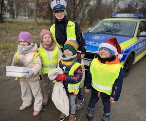 Dzieci z policjantką i naszykowanymi prezentami oraz rózgami.