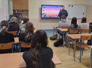 Umundurowany policjant rozmawia z młodzieżą w klasie.