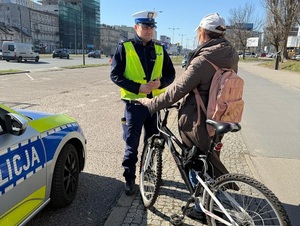 Policjant Wydziału Ruchu Drogowego Komendy Miejskiej Policji w Łodzi kontroluje rowerzystę.