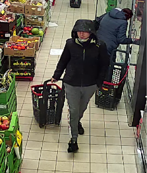 Mężczyzna w wieku około 30 lat, wzrost około 170 centymetrów, ubrany w czarną kurtkę z kapturem, szare spodnie i czarne buty sportowe.