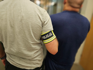 Policjant trzyma zatrzymanego mężczyznę.