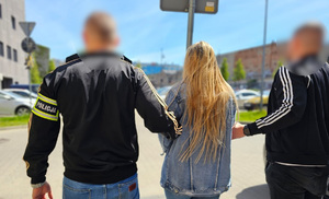 Policjanci trzymają zatrzymaną kobietę.
