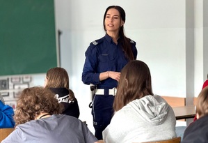 Umundurowana policjantka w trakcie zajęć z młodzieżą w klasie.