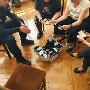 Policjant prezentuje pedagogom walizkę z materiałami edukacyjnymi na temat narkotyków i dopalaczy.