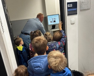 Przedszkolaki patrzą na pracę technika kryminalistyki.