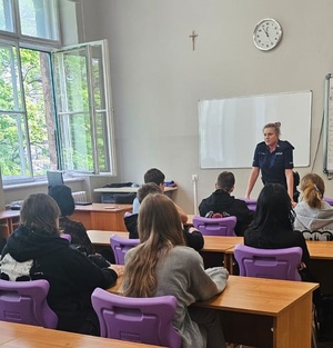 Umundurowana policjantka w trakcie zajęć z młodzieżą w klasie.