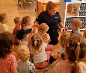 Policjantka prezentuje dzieciom tarcze do zatrzymywania pojazdów.