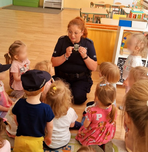 Policjantka prezentuje dzieciom odznakę policyjną.