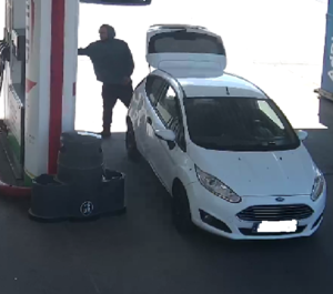 Mężczyzna w wieku od 30 do 40 lat, szczupłej budowy ciała. Ubrany w ciemne buty, ciemne spodnie, granatową bluzę z kapturem.