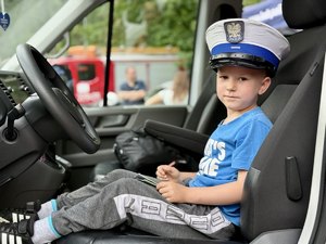 Dziecko siedzące za kierownicą radiowozu.
