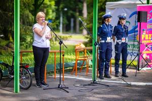 Kobieta mówiąca przez mikrofon, obok niej stoją policjantki.